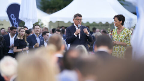 Ministerpräsident Boris Rhein (Mitte) – mit Mikrofon in seiner rechten Hand – und Staatsministerin Lucia Puttrich (rechts) inmitten der Gäste auf dem Hessenfest in Berlin