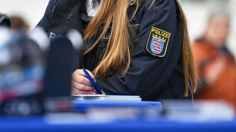 Polizistin sitzt am Tisch und hält einen Stift, um etwas mitzuschreiben