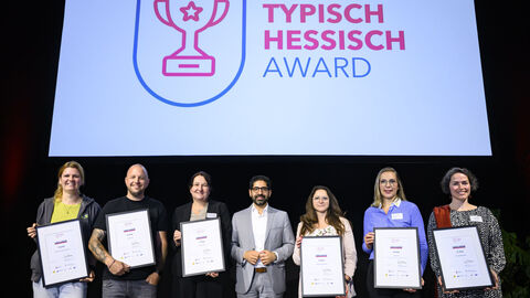 Mehrere Personen stehen mit Urkunden in der Hand auf einer Bühne